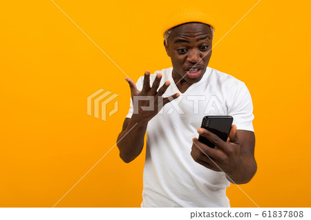 black man looks in surprise on the phone on an orange background black man looks in surprise on the phone on an orange background 61837808