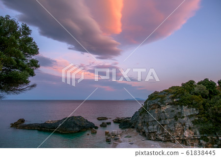 Sunset Clouds Over a Small Rocky Beach 61838445