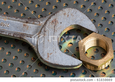 Wrench and brass plumbing fittings on metallic background close-up Wrench and brass plumbing fittings on metallic background close-up 61838669