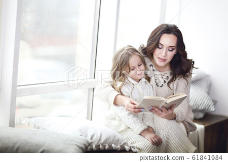 Mother reading a book to a daughter 61841984
