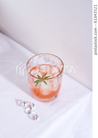 Pink cocktail with rosemary and ice in glass on a white tablecloth on the table Pink cocktail with rosemary and ice in glass on a white tablecloth on the table 61843521