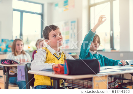 Boy student in class knowing an answer raising his hand Boy student in class knowing an answer raising his hand 61844163