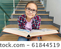 Girl is reading book while sitting on stairs 61844519
