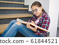 Girl is reading book while sitting on stairs 61844521