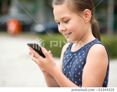 Little girl is using smartphone Little girl is using smartphone 61844529