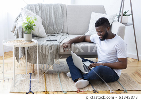 Positive african man surfing internet on laptop 61845878
