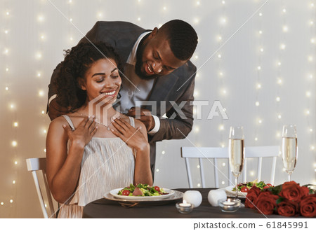 Gallant african man putting golden necklace on his woman Gallant african man putting golden necklace on his woman 61845991