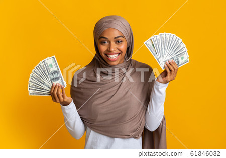 Overjoyed Black Muslim Girl in Hijab Holding Lots Of Dollar Cash Overjoyed Black Muslim Girl in Hijab Holding Lots Of Dollar Cash 61846082