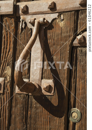 Iron puller and hinge with studs in an old wooden door 61846212