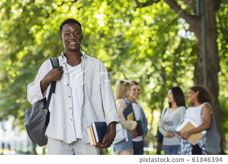 Happy afro student with books smiling at camera Happy afro student with books smiling at camera 61846394