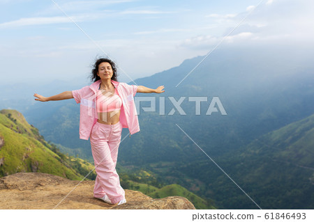 Girl enjoys a mountain view while standing on a Girl enjoys a mountain view while standing on a 61846493