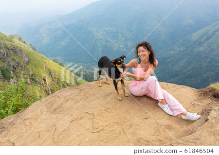 A girl with a dog enjoying the mountain scenery on A girl with a dog enjoying the mountain scenery on 61846504