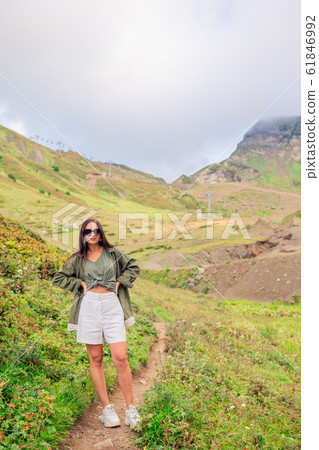 Beautiful happy young woman in mountains in the background of fog 61846992