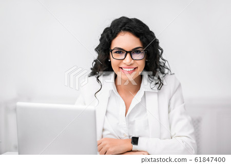 Happy hispanic manager smiling at camera in office Happy hispanic manager smiling at camera in office 61847400