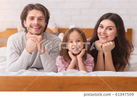 Happy family of three posing on bed at home together 61847509