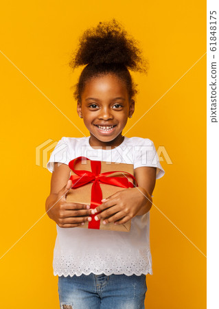 Cheerful afro girl holding gift box, yellow background 61848175