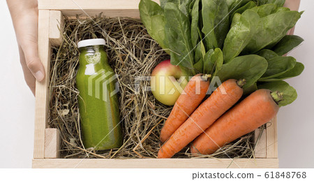 Woman farmer holding wooden box with detox drink 61848768