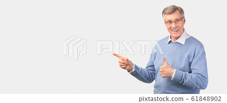 Senior Gentleman Gesturing Thumbs-Up Pointing Fingers Aside On White Background Senior Gentleman Gesturing Thumbs-Up Pointing Fingers Aside On White Background 61848902