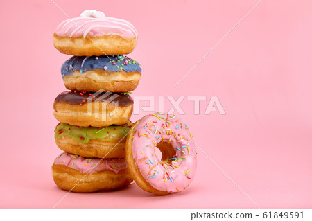 Sweet donuts stacked in a stack on a pink background. Copy space, game of color, sweet life. 61849591