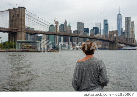 Woman tourist enjoying view of Brooklyn Bridge and Manhattan skyscrapers Woman tourist enjoying view of Brooklyn Bridge and Manhattan skyscrapers 61850007