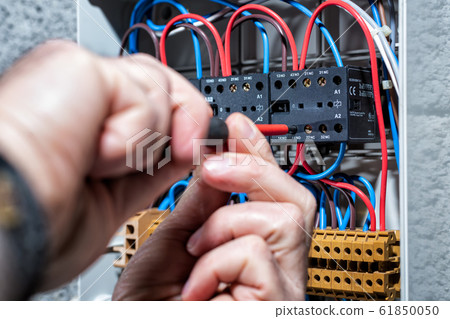Electrician working on a residential electrical Electrician working on a residential electrical 61850050