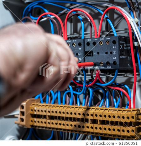 Electrician working on a residential electrical Electrician working on a residential electrical 61850051