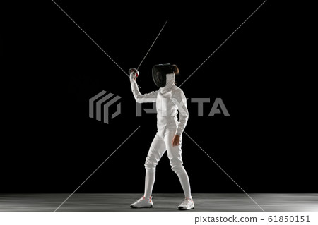 Teen girl in fencing costume with sword in hand isolated on black background 61850151