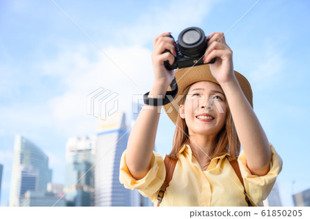Young woman taking photograph against buildings in background in Singapore Young woman taking photograph against buildings in background in Singapore 61850205