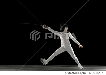 Teen girl in fencing costume with sword in hand isolated on black background 61850214