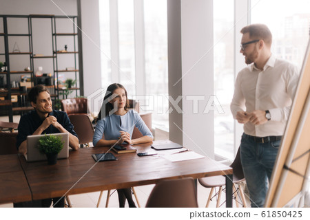 Young casual businessman presenting new project to partners Young casual businessman presenting new project to partners 61850425