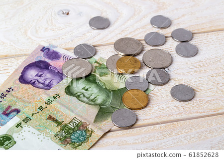 Chinese yuan banknotes and coins on a white wooden surface. 61852628