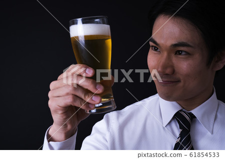 Young businessman drinking beer (black background, tie, glass beer 61854533
