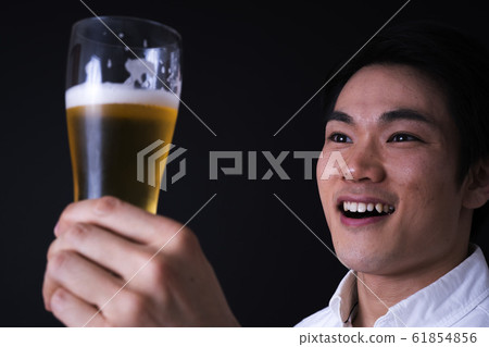 年輕的商人喝啤酒（黑色背景，領帶，玻璃啤酒 61854856