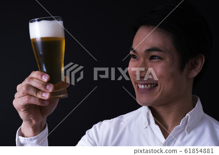 年輕的商人喝啤酒（黑色背景，領帶，玻璃啤酒 61854881