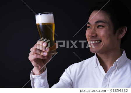 年輕的商人喝啤酒（黑色背景，領帶，玻璃啤酒 61854882