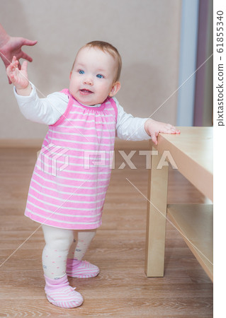 Happy caucasian little girl learning to walk with Happy caucasian little girl learning to walk with 61855340
