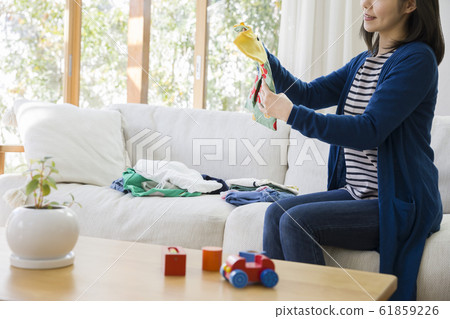 年輕的家庭主婦,手拿童裝 年輕的家庭主婦,手拿童裝 61859226