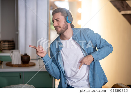 Emotional young man dancing while listening favourite music Emotional young man dancing while listening favourite music 61860813