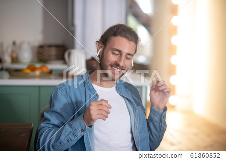 Smiling man enjoying his favourite song in wireless earphones 61860852