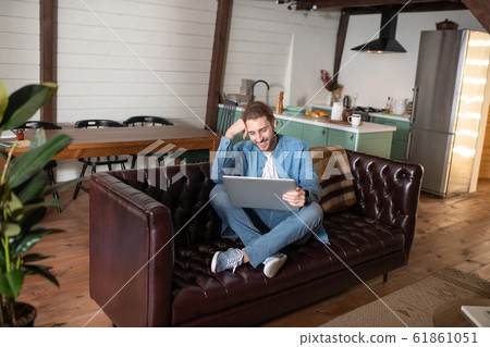 Smiling man working with his laptop at home Smiling man working with his laptop at home 61861051