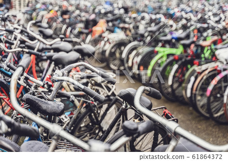 Blurred background of different bicycles in the parking lot. Parked bicycles in Amsterdam Blurred background of different bicycles in the parking lot. Parked bicycles in Amsterdam 61864372