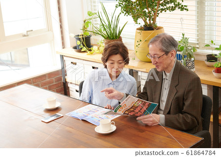 年長的夫婦在旅行諮詢,同時看著小冊子去哪裡 年長的夫婦在旅行諮詢,同時看著小冊子去哪裡 61864784