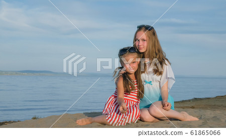Two teenage children are sitting on the beach. Two teenage children are sitting on the beach. 61865066