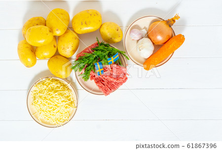 Ingredients for stuffed potatoes. Potatoes, minced meat, onion, carrot, cheese, garlic. Swedish cuisine. Scandinavian food. Background Ingredients for stuffed potatoes. Potatoes, minced meat, onion, carrot, cheese, garlic. Swedish cuisine. Scandinavian food. Background 61867396