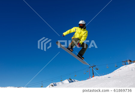 Bright color snowboarder jumps on blue sky Bright color snowboarder jumps on blue sky 61869736