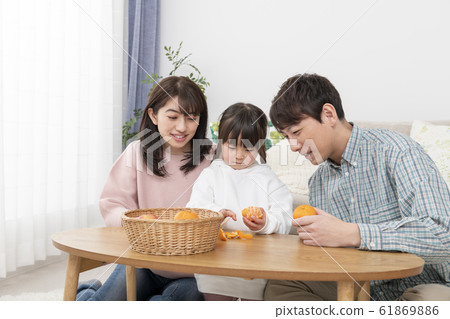 A girl peeling oranges and parents watching over her family image 61869886