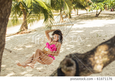Sexy slim girl enjoys relaxing in a hammock on the Sexy slim girl enjoys relaxing in a hammock on the 61871176