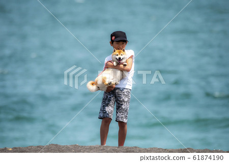 A boy holding a bean bush against the sea 61874190