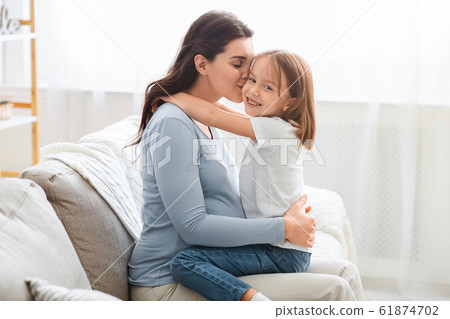 Pregnant woman kissing her cute little daughter 61874702