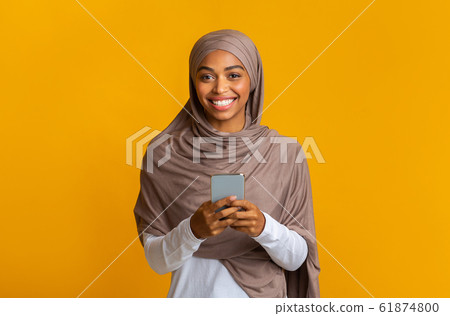 Cheerful Afro Muslim Girl In Hijab With Smartphone In Hands 61874800
